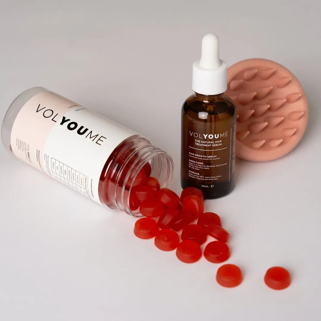 Gummies spilling from the jar beside the serum and the massager