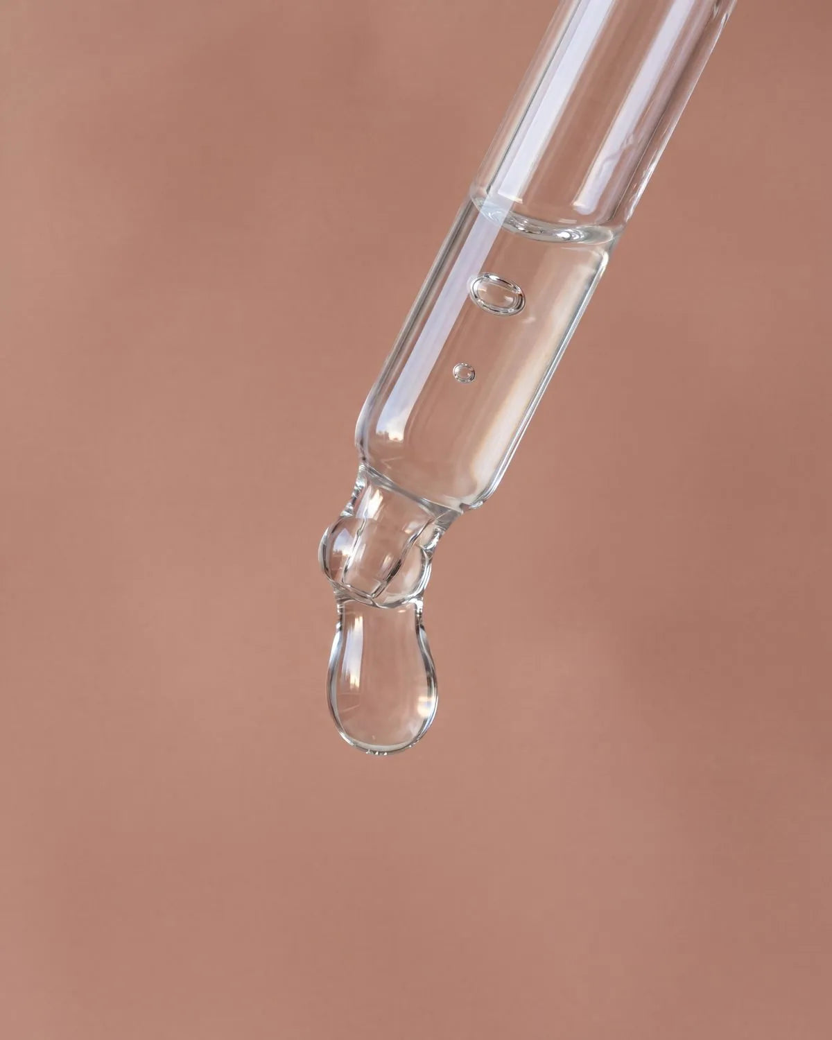 A clear drop of serum falling from the dropper